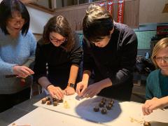 Samurai Miso Soup Making Experience in Nishio Aichi Four people are gathered around a table, working on small chocolate balls decorated with what appear to be pretzels and crackers, likely as part of a food-making experience.