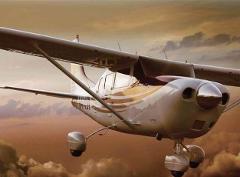 A low-angle, close-up view of a Cessna aircraft in flight, with clouds in the background.