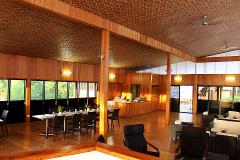 This interior shot displays Lake Murray Lodge's warm dining and lounge area with wood finishes, tables, chairs, sofas, and a textured ceiling.