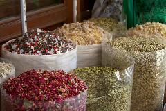 This vibrant image showcases an array of colorful spices and herbs displayed in sacks or plastic containers, likely at a market or spice shop.