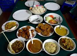A table is set with a variety of dishes in bowls and on plates, suggesting a shared meal or buffet-style spread.