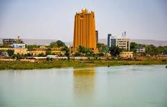 A striking golden-hued building rises from a waterfront cityscape, its reflection shimmering on the water.