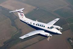 A Royal Air Force Beechcraft King Air flying over rural fields.