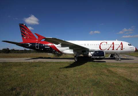 The image shows a CAA Airbus A320 passenger plane on the ground, with a unique red, white, and blue livery featuring stars.