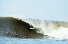 A surfer rides a large, barreling wave.