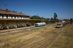 A vintage train station with old carriages on multiple tracks under a clear blue sky.