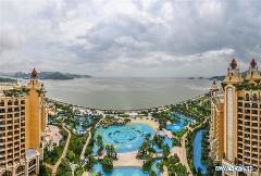 Overhead shot of a resort with pools and buildings along a coastline on a cloudy day.