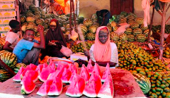 A vibrant market scene with people selling and displaying watermelons.