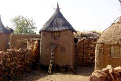 This image shows traditional mud brick architecture with thatched roofs in a village setting, likely in a rural African community.