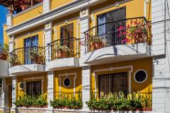 Parque Nacional Natural Tayrona Tour de 2 días desde Cartagena A yellow building with white trim featuring balconies with potted plants and window boxes filled with greenery.