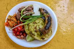 这个盘子里装满了各种烤制食物：香肠、玉米饼、碎肉、奶酪、葱、番茄沙拉和胡萝卜沙拉。