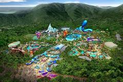 This is an aerial view of a large amusement park built in a mountainous, forested area, featuring a variety of rides and attractions.