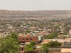 A wide shot reveals a dense town nestled against a hazy, arid landscape.