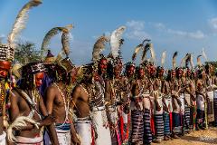 Bianou and Gerewol Festival Combo Package – 12 Days A line of Wodaabe men in traditional attire with red face paint, feathered headdresses, and beaded necklaces stand during the Gerewol festival.