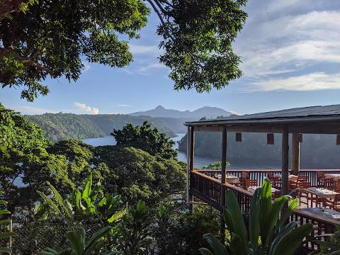 Overlooking a serene bay surrounded by lush forests, the Tufi Resort's veranda offers stunning views of the distant mountains.