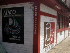 A corner view of a brick building with painted advertisements for "Café Ataco," featuring a woman in traditional garb and a large coffee cup design.