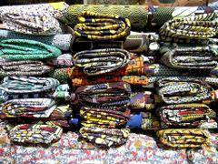 A colorful display of folded African wax print fabrics stacked on a patterned table.