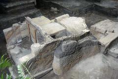 A high-angle shot captures an archaeological site featuring earthen structures and potential remnants of ancient architecture.