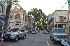 A street scene features parked Toyota SUVs facing each other on a city street lined with weathered buildings and trees.