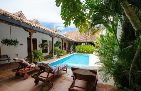 Mompox & Aracataca Cultural Journey (3 Days / 2 Nights) A serene courtyard with a swimming pool, lounge chairs, and lush greenery, typical of a tropical getaway.