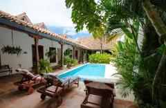 Mompox & Aracataca Cultural Journey (3 Days / 2 Nights) A serene courtyard with a swimming pool, lounge chairs, and lush greenery, typical of a tropical getaway.