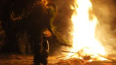 A blurry image captures a Baining Fire Dance performance in Papua New Guinea, featuring a dancer in traditional garb beside a roaring fire.