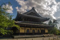 Tokyo & Kyoto Private Garden Tour: A Complete 6-Day Journey Through Japan's Most Beautiful Gardens This image depicts a traditional Japanese temple with its characteristic multi-tiered roof, set against a backdrop of lush greenery and a partly cloudy sky, showcasing classic architectural design.
