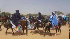 A vibrant scene from the Bianou Festival in Niger, showcasing riders on decorated horses, likely part of a traditional parade.