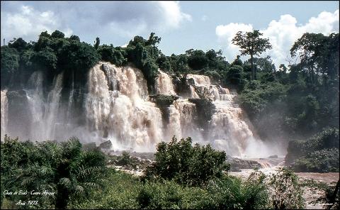 A scenic view of the Chutes de Boali waterfall cascading down multiple tiers amidst lush greenery in the Central African Republic, captured in August 1978.