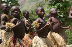 Eine Gruppe afrikanischer Kinder trägt traditionelle Strohröcke und führt einen kulturellen Tanz auf.