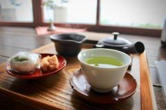 A serene Japanese tea setting with a cup of green tea, traditional sweets, and a teapot on a wooden tray, creating a calming and authentic atmosphere.