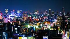 Se trata de un paisaje urbano vibrante por la noche, con numerosos edificios iluminados por luces de colores que crean una escena urbana animada y dinámica.