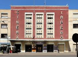 The image shows the "Cinema Impero," an Art Deco-style building with a prominent facade featuring vertical lettering and decorative windows.