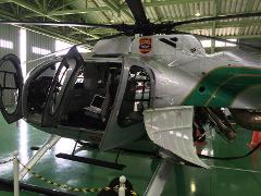 A helicopter with its doors open, revealing a laptop inside, sits in a hangar.