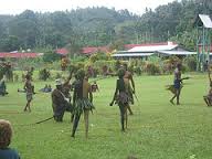 Certainly! Here's a description of the image within the character limit:The image shows a group of people performing a traditional dance on a grassy field, possibly at a cultural event near the Rabaul WWII Memorial.