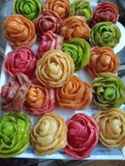 A tray filled with colorful, flower-shaped treats in shades of green, orange, red, and yellow.
