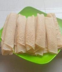 A green plate holding several beige, rolled pancakes, each with a noticeable textured surface.