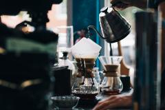 Coffeeholic Tour in Medellin A person is pouring water from a kettle into a coffee filter on top of a glass carafe to make pour-over coffee.
