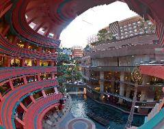 This is a unique urban landscape featuring a terraced, curvilinear building complex with red and green accents, surrounding a waterway.