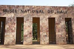 14-Day Ethnic Trip to Bamako, Sibi and Ségou The image shows the entrance to the National Museum of Mali, featuring a stone facade with the museum's name in black letters, and five openings with black metal doors.