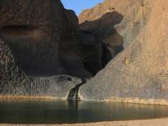 A scenic view of a secluded desert oasis with cascading waterfalls and unique rock formations.