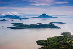 An aerial view of several islands dotting a large body of water under a partly cloudy sky.