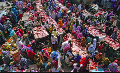 An aerial view shows a crowded outdoor market in Mogadishu, Somalia, with vendors selling meat from tables and customers milling around to purchase.