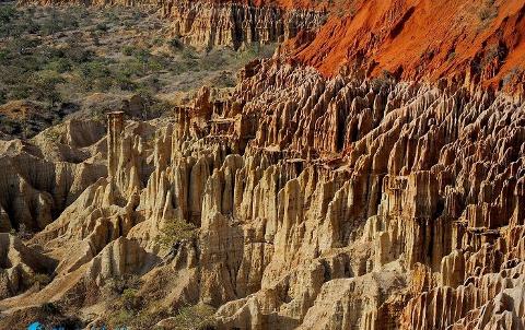 This landscape shows unusual, layered rock formations of beige and red colors, creating a striking, desert-like terrain.