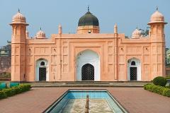 This image features the tomb of Bibi Pari at Lalbagh Fort, a magnificent structure with a dome, arched entrances, and a salmon-pink facade, standing majestically against a clear sky.