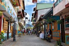 Gran Tour incluyendo Bogotá, Medellín, Nuquí y Valle del Cocora - 11 Días A vibrant, narrow street lined with colorful buildings and hanging plants in a charming town, bustling with tourists and local life.