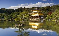 Une vue sereine du Kinkaku-ji, le Pavillon d&#39;or, se reflétant dans un étang entouré d&#39;une verdure luxuriante sous un ciel partiellement nuageux.