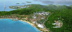 A panoramic view of a coastal resort city, featuring sandy beaches, lush greenery, a Ferris wheel, and modern architecture along the coast.