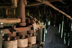 Katanzama Indigenous Community Hiking Tour with Poza Sagrada Visit A rustic interior features a weathered wooden structure with bucket-like elements and a central column, bathed in dappled light filtering through the slatted walls.