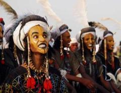 Certainly! Here's a description of the image in one sentence and under 320 characters:The image shows men adorned in traditional attire, including intricate face paint, feathered headdresses, and beaded necklaces, likely participating in the Gerewol festival.